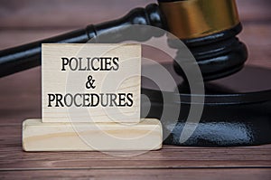 Policies and procedures text engraved on wooden block with gavel background. Policy and procedure concept