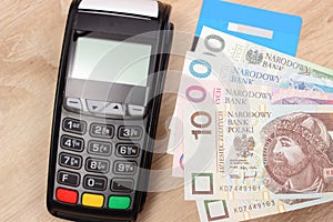 Polish currency money and credit card with payment terminal in background, finance concept
