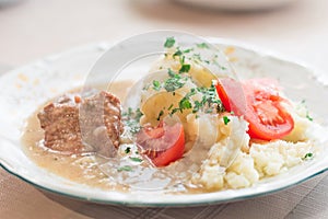 Polish dish bitki wolowe with sauce, smashed potatoes with parsley and tomato