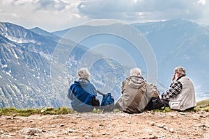 Polish Tatras Poland June 3 2019: elderly people with backpacks are sitting on the ground high in the mountains. An old man looks