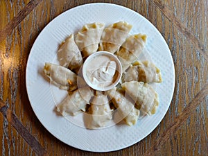 Polish traditional filled pirog served on white plate with mayonnaise in the small bowl