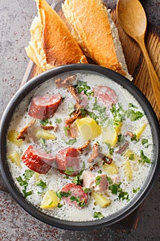 Polish Zalewajka soup on rye sourdough with root vegetables, smoked sausage, dried mushrooms and bacon close-up in a plate on the