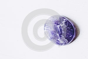 Polished amethyst tumbled stone pebble on a white background with empty space