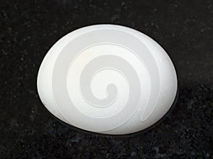 polished cacholong (white opal) gemstone on dark photo