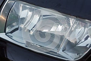 Polished car headlight in black car body