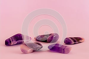 Polished dogtooth amethyst gemstones on pink background