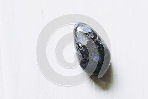 Polished glaucophane gemstone on a white background