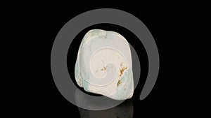 Polished mineral stone zoisite rotates in a circle on a black background