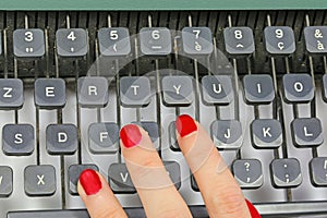 polished nails of Female secretary typing on the keys of an old typewriter