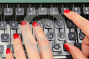 polished nails of Female secretary typing on the keys of an old typewriter in an office