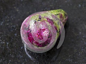 polished pink and green zoisite gemstone on dark