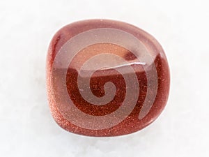 polished red goldstone gemstone on white marble
