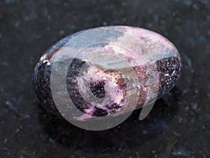 polished Rhodonite gemstone on dark background photo