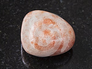 polished sunstone (heliolite) gem stone on dark