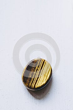 Polished tiger eye tumbled stone pebble on a white background with empty space