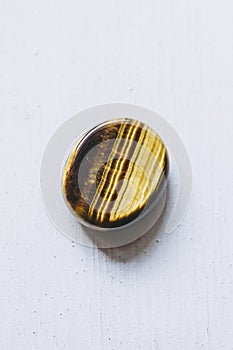 Polished tiger eye tumbled stone pebble on a white background with empty space