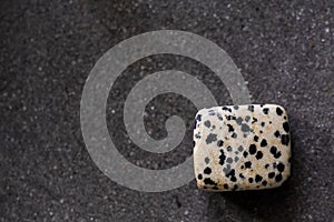 Polished tumbled dalmatien jasper stone on a black background