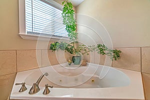 Polished white built in bathtub with stailess steel faucet at bathroom corner photo