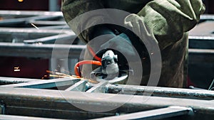 Polishing welding seams with angle grinder at plant. Using industrial instrument