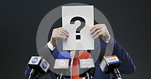 Politician hiding his face with a sign during a press interview