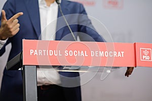 A politician is holding a press conference at a desk of the Social Democratic Party Partidul Social Democrat, PSD