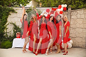 Polka dot birthday party. Group of female friends enjoying and laughing. Women in dresses having fun by Photo zone from red and