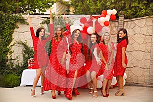 Polka dot birthday party. Group of female friends enjoying and laughing. Women in dresses having fun by Photo zone from red and