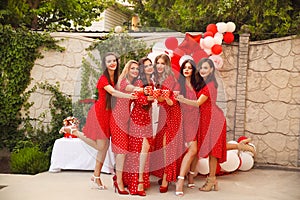 Polka dot birthday party. Group of female friends enjoying and laughing. Women in dresses having fun by Photo zone from red and