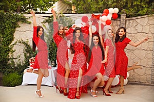 Polka dot birthday party. Group of female friends enjoying and laughing. Women in dresses having fun by Photo zone from red and