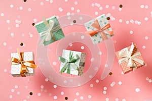 Polka dot pattern gift box with ribbon falling on pink background, levitation