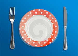 Polka dot red plate with fork and knife top view