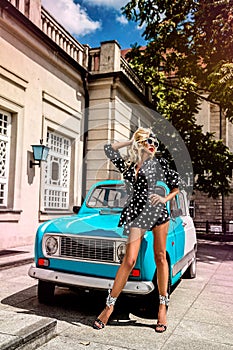 Polka dots fashion. Beautiful blonde young woman near the car . Spring and summer fashion model concept. Rose bear.