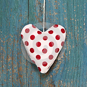 Polka dotted heart on turquoise wooden surface in country style.