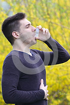 Pollen allergy, boy using asthma inhaler in park