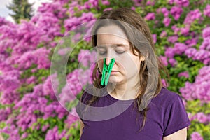 Pollen allergy concept. Young woman cant breathe and wearing peg on her nose.