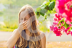 Pollen allergy concept. Young woman is going to sneeze. Flowering trees in background