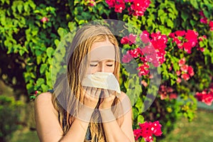 Pollen allergy concept. Young woman is going to sneeze. Flowering trees in background