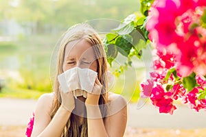 Pollen allergy concept. Young woman is going to sneeze. Flowering trees in background