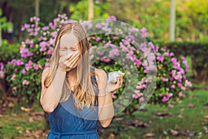 Pollen allergy concept. Young woman is going to sneeze. Flowering trees in background