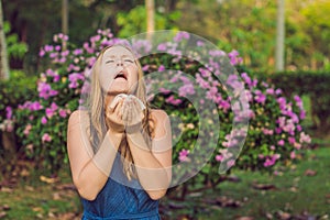 Pollen allergy concept. Young woman is going to sneeze. Flowering trees in background