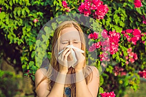 Pollen allergy concept. Young woman is going to sneeze. Flowering trees in background