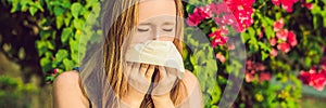Pollen allergy concept. Young woman is going to sneeze. Flowering trees in background BANNER, long format