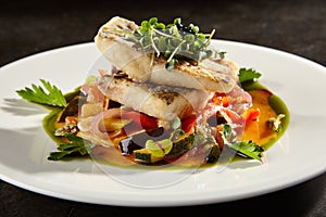 Pollock fish fillet with vegetables on white plate