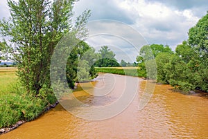 Polluted river orange green trees countryside