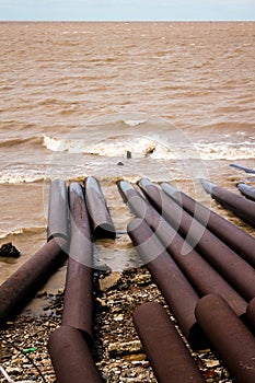 Polluted sea with rusty pipelines on the shore