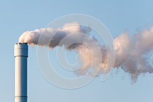 Polluted smoke against a clear blue sky from the tall chimney