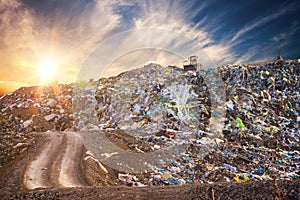Pollution concept. Garbage pile in trash dump or landfill at sunset photo