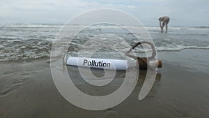 Pollution message inside the glass bottle dragged by the abandoned tide on the beach