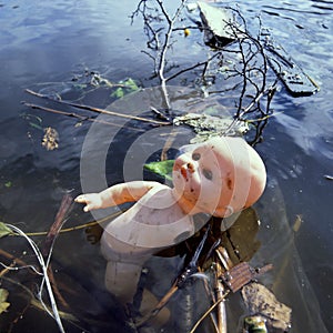 Pollution in public water by a discard,plastic toy doll