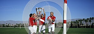 Polo team celebrating with trophy on field